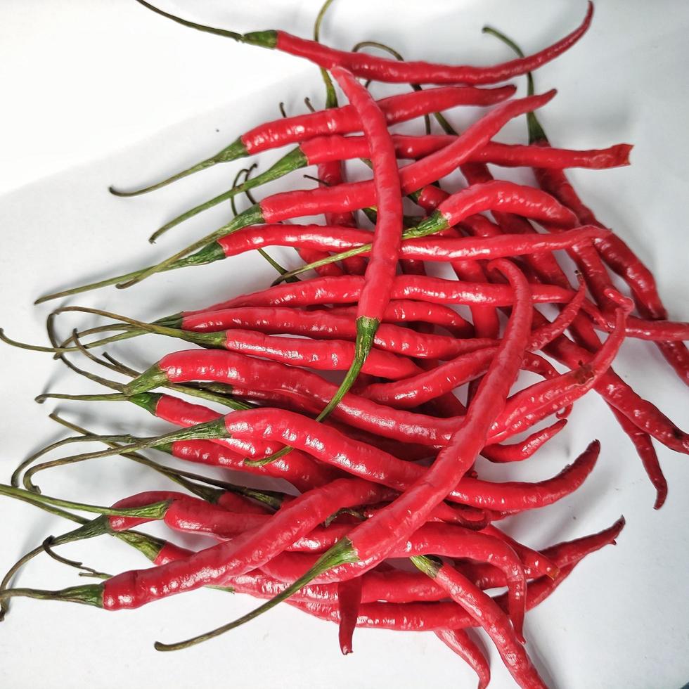 en hög med färska långa röda chili med vit bakgrund foto