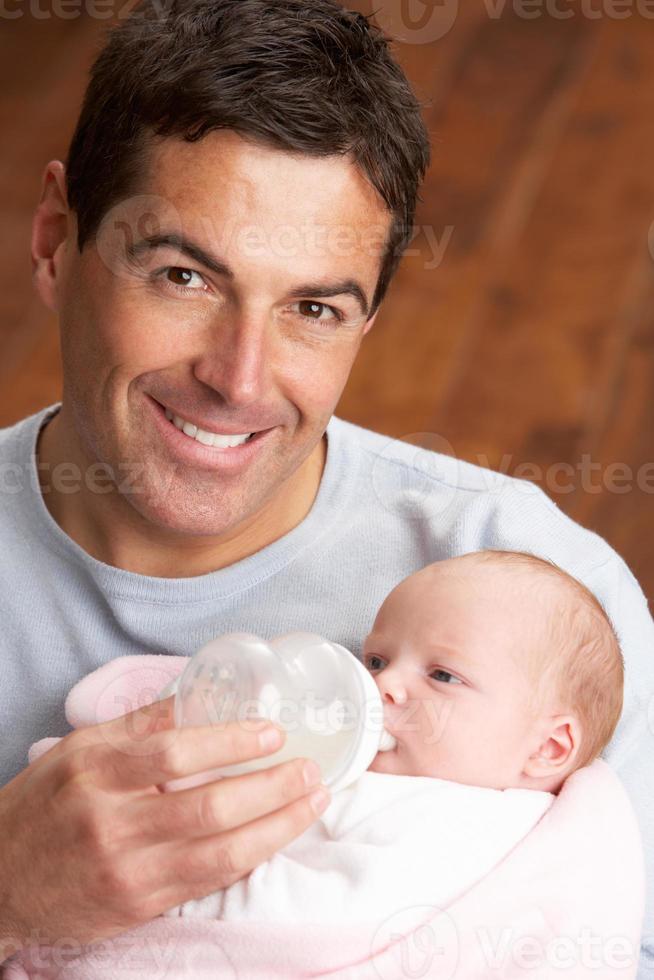 porträtt av far som matar nyfött barn hemma foto