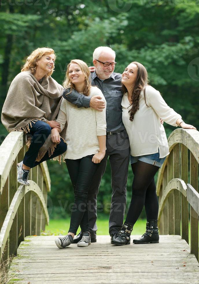 lycklig familj som står tillsammans på en bro i skogen foto