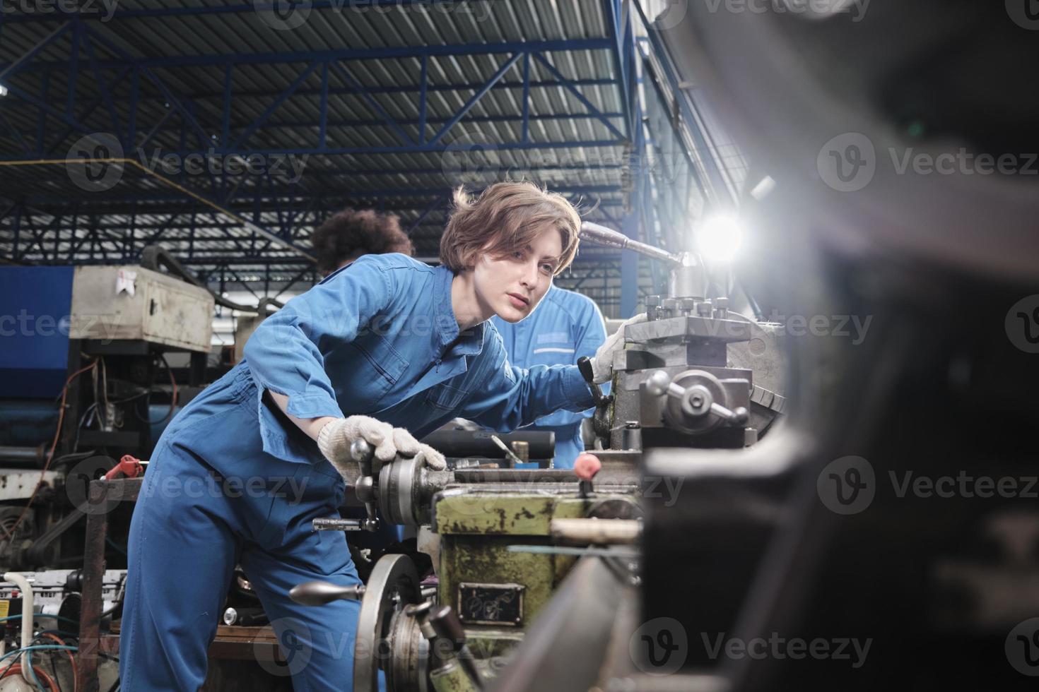 professionell ung vit kvinnlig industriingenjörsarbetare arbetar i säkerhetsuniform med precisionsverktyg för metallarbete, mekaniska svarvmaskiner och reservdelsverkstad i ståltillverkningsfabriken. foto