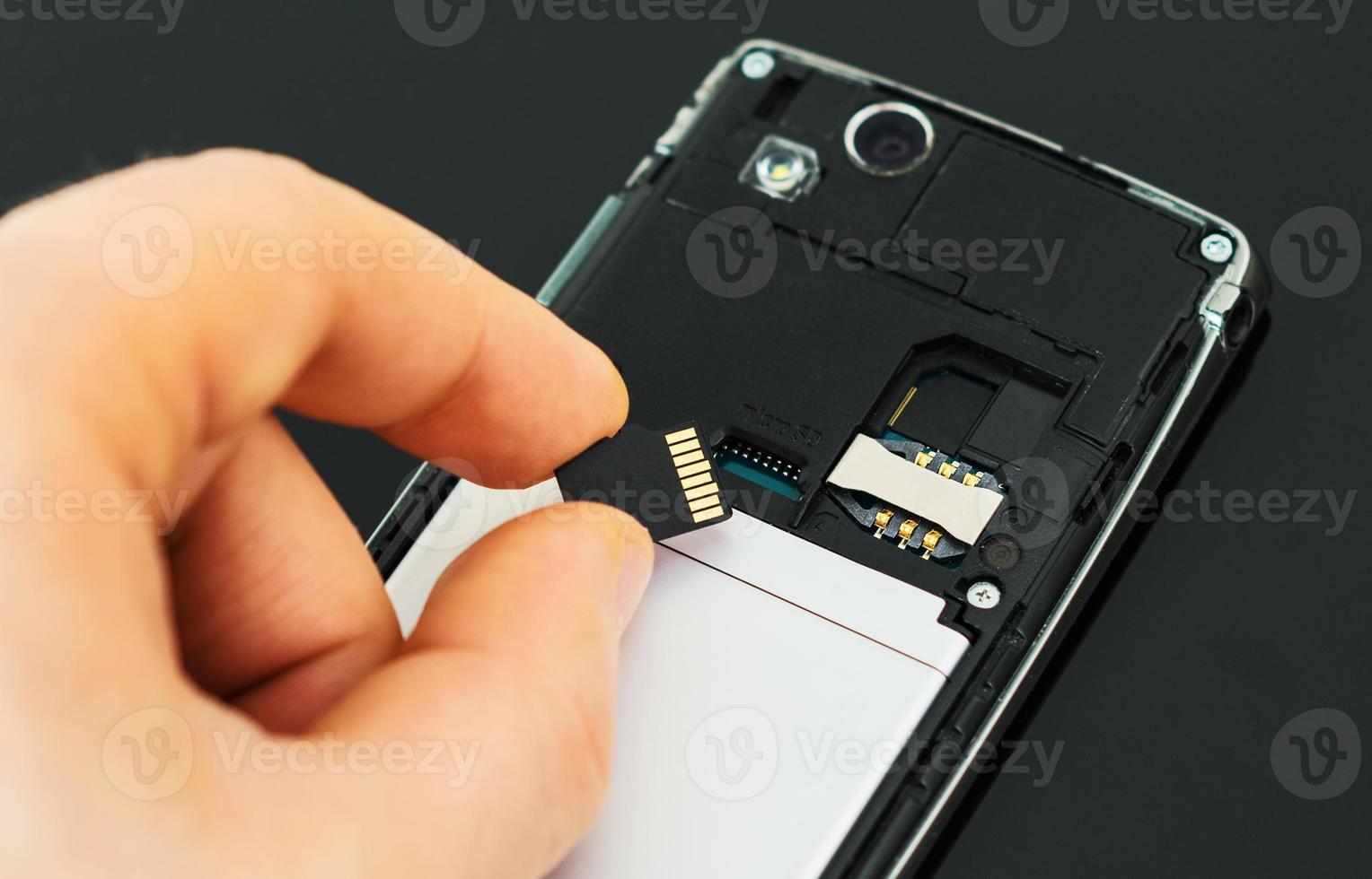 manlig hand som sätter in mikro-SD-kort till mobiltelefonen. foto