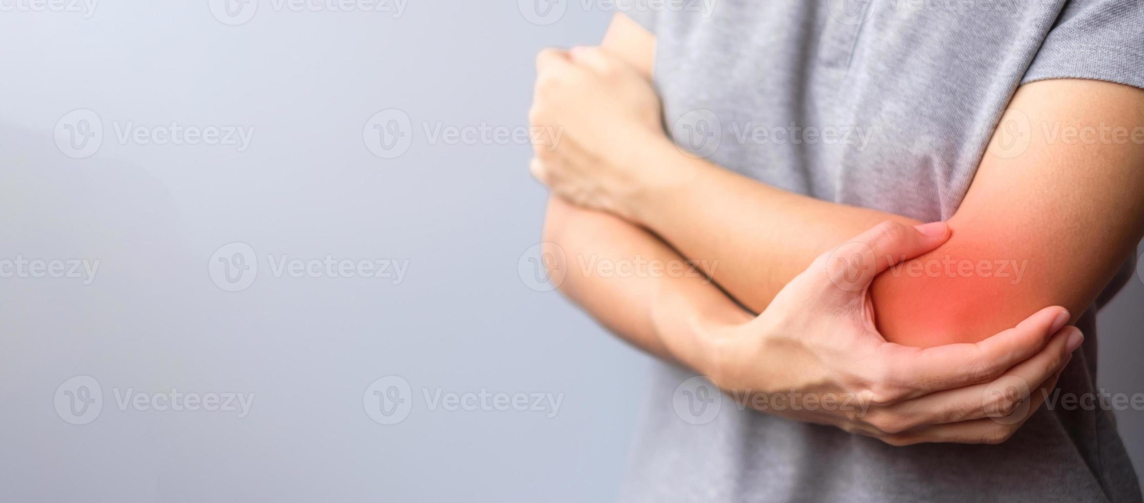 vuxen kvinna med sin muskelsmärta på grå bakgrund. kvinna som har armbågsvärk på grund av lateral epikondylit eller tennisarmbåge. skador och medicinsk koncept foto