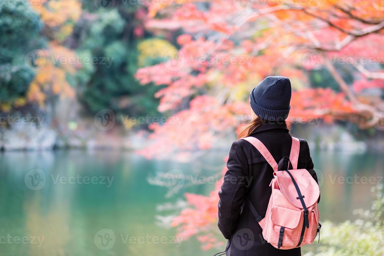 glad kvinna turist ser färgglada löv och katsura floden i arashiyama, ung asiatisk resenär besöker i Kyoto och njuter av resor i Japan. höst höstsäsong, semester, semester och sightseeing koncept foto