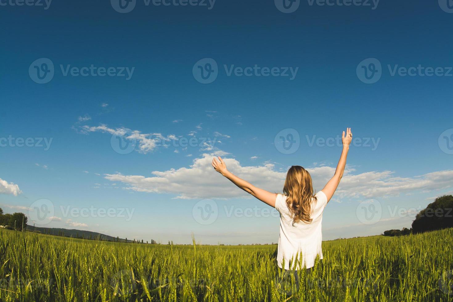 ung kvinna som njuter av naturen och solljus i vetefältet foto