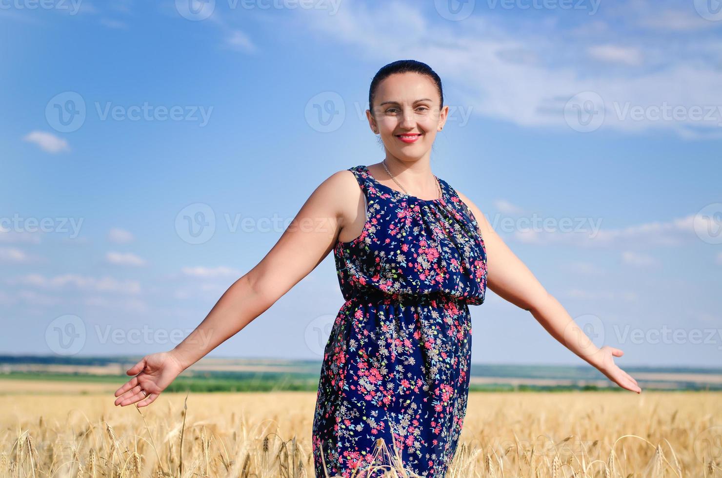 kvinna stående njuter av solen i ett vetefält foto