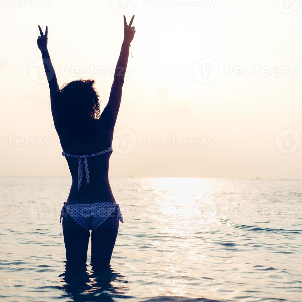 kvinna som njuter av frihet och känner sig lycklig vid stranden vid solnedgången foto