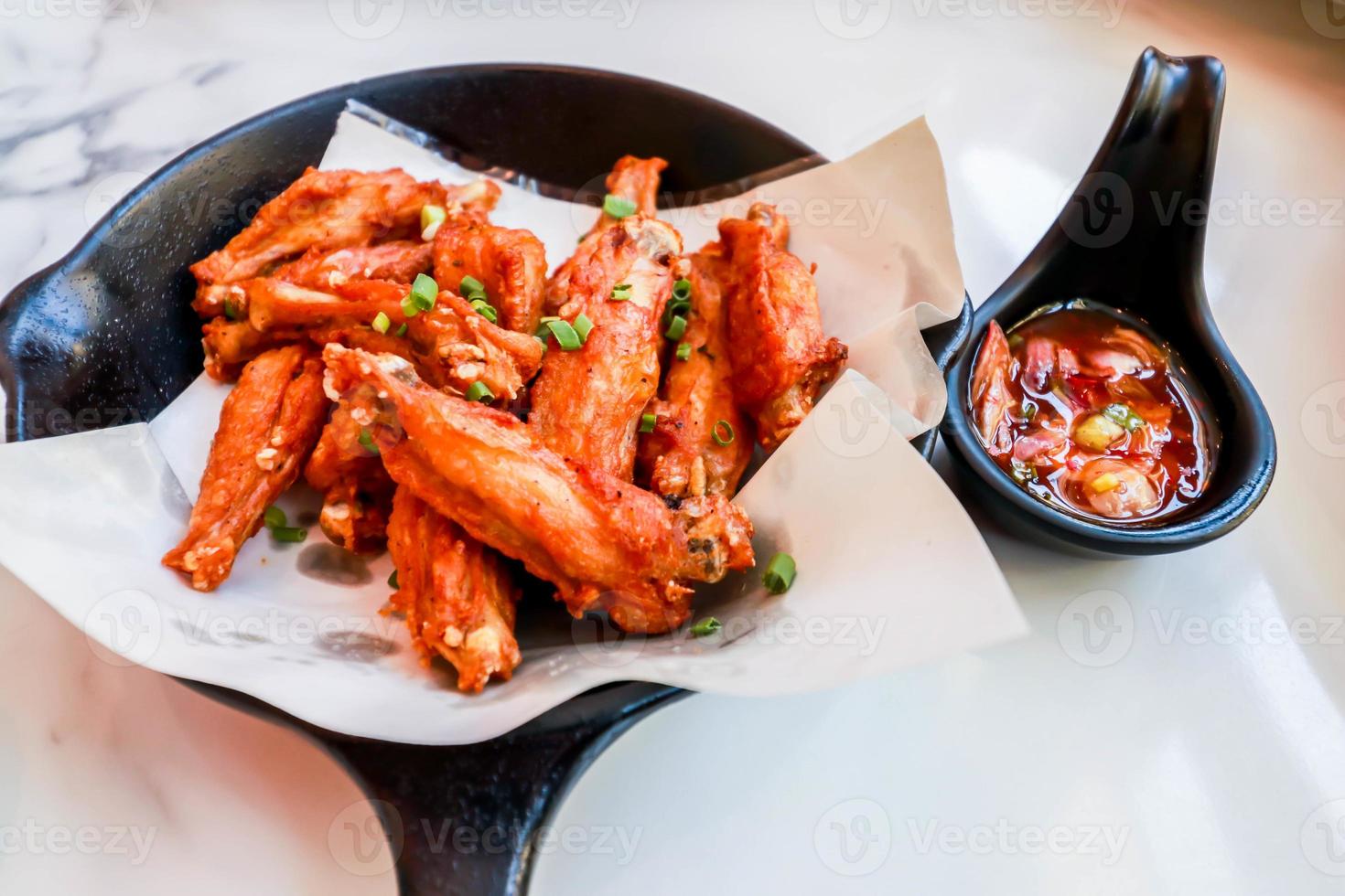 närbild av thailändska salt stekt kycklingvinge med chili saus foto