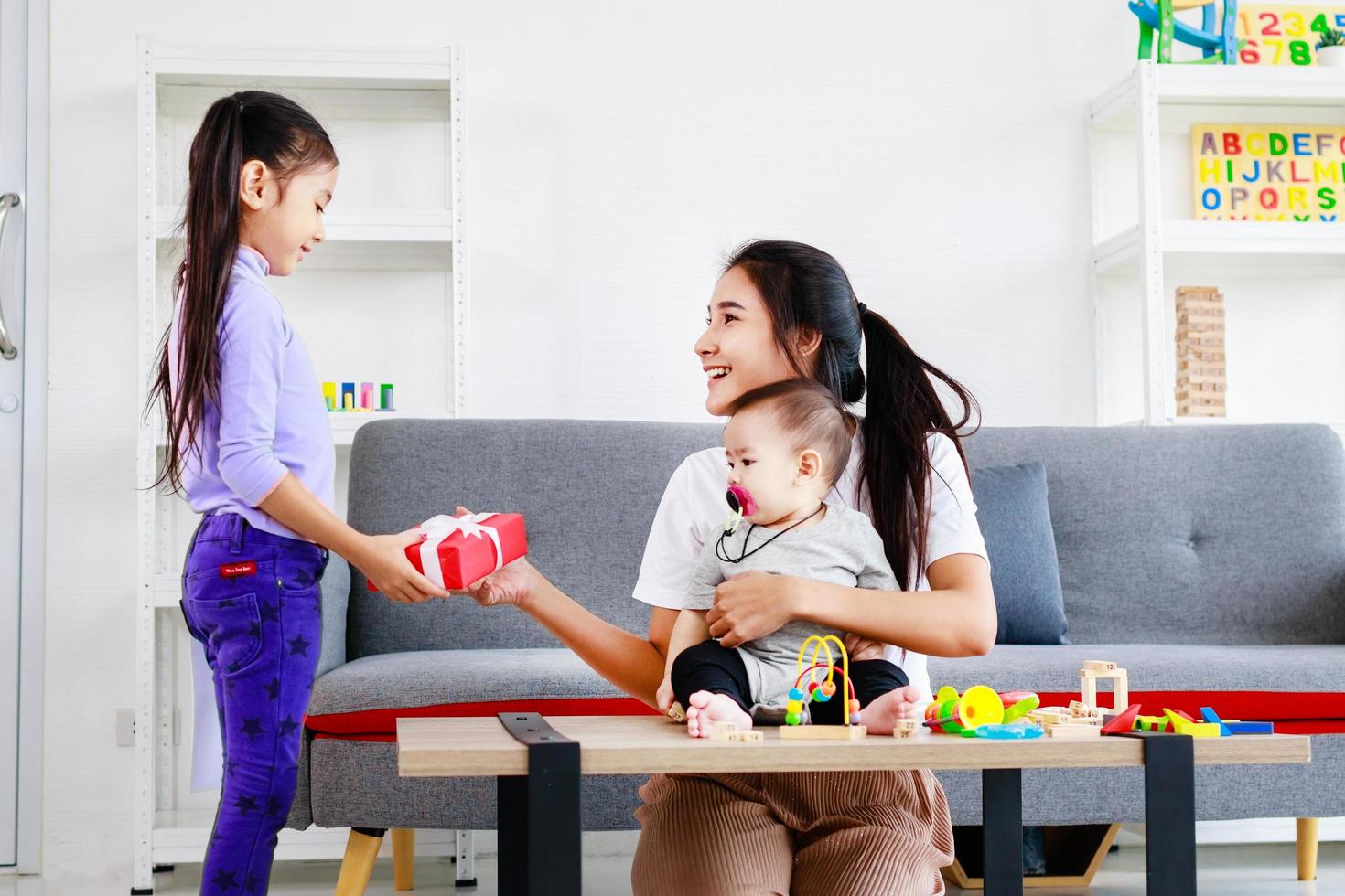 söt dotter skickar kärleksmamma-kort till mamma och kysser medan ta hand baby foto