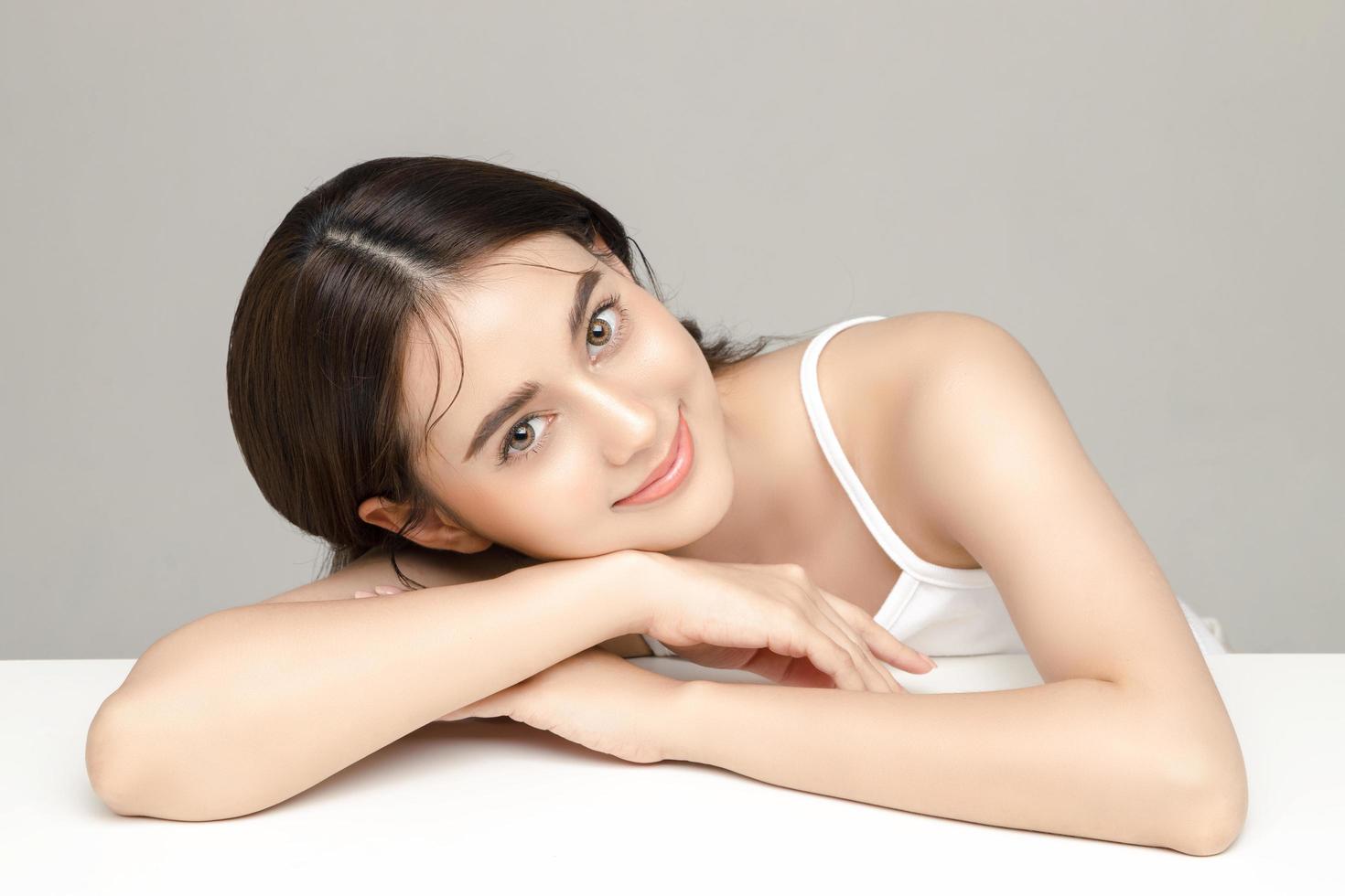 vacker ung asiatisk kvinna modell med perfekt ren fräsch hud på grå bakgrund. ansiktsvård, ansiktsbehandling, kosmetologi, plastikkirurgi, härlig tjejporträtt i studio. foto