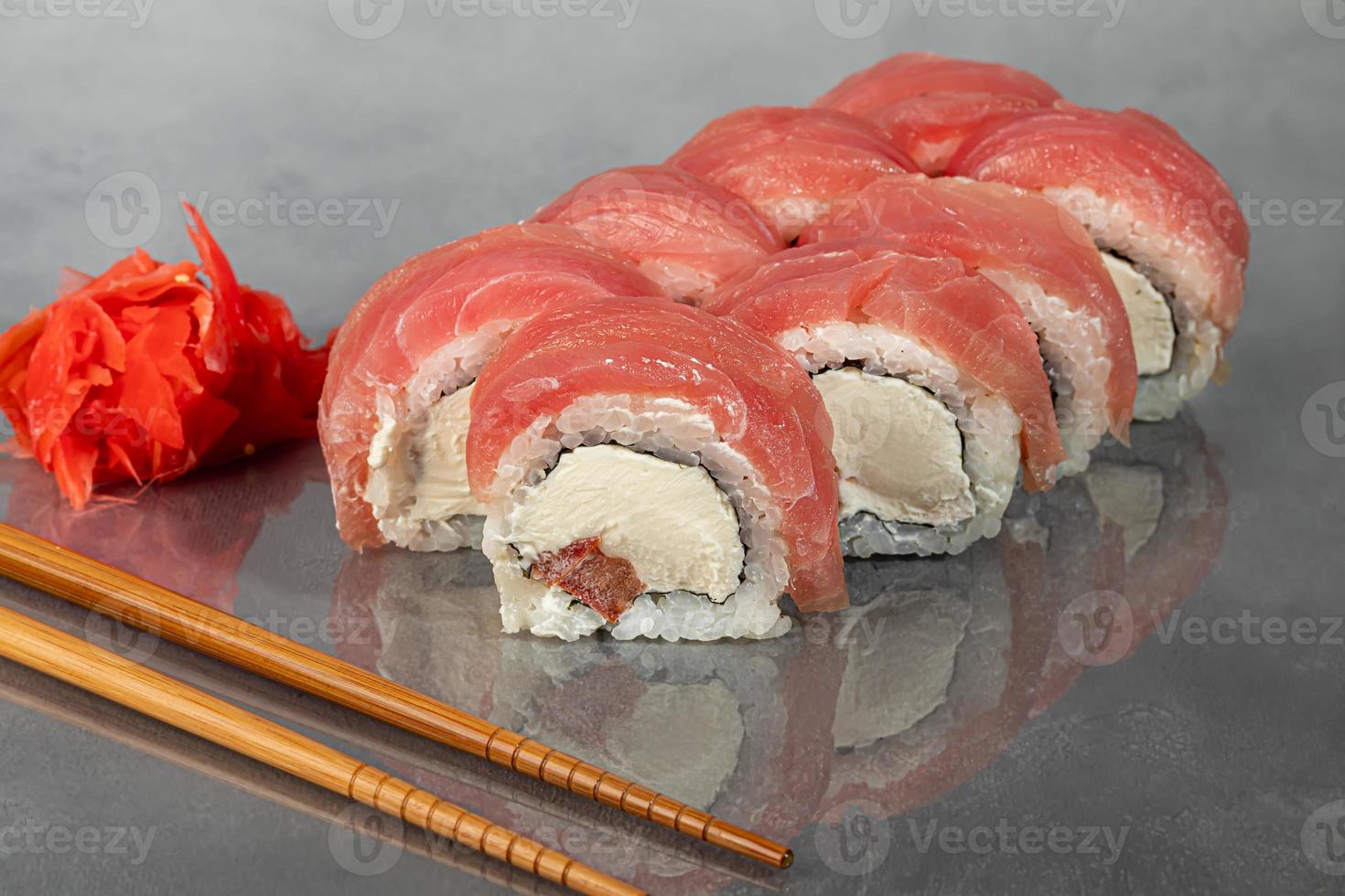 sushi set uramaki, kalifornien, philadelphia, rullar på en vit platta. meny för restauranger, caféer. på en mörk reflekterande bakgrund. foto