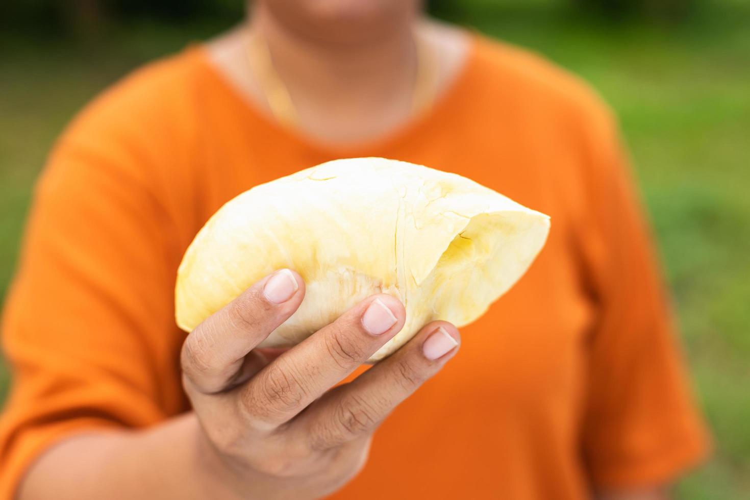 närbild händer kvinna som håller bit av skal durian frukt foto