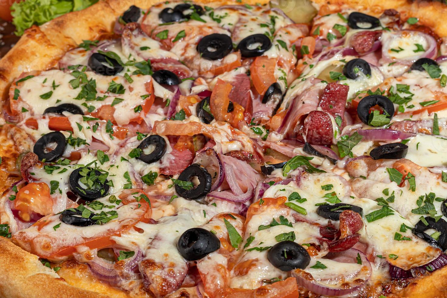 pizza med bacon och ost, örter och körsbärstomater. med mozzarella, räkor och bläckfiskar, musslor och andra produkter på en träbakgrund. foto