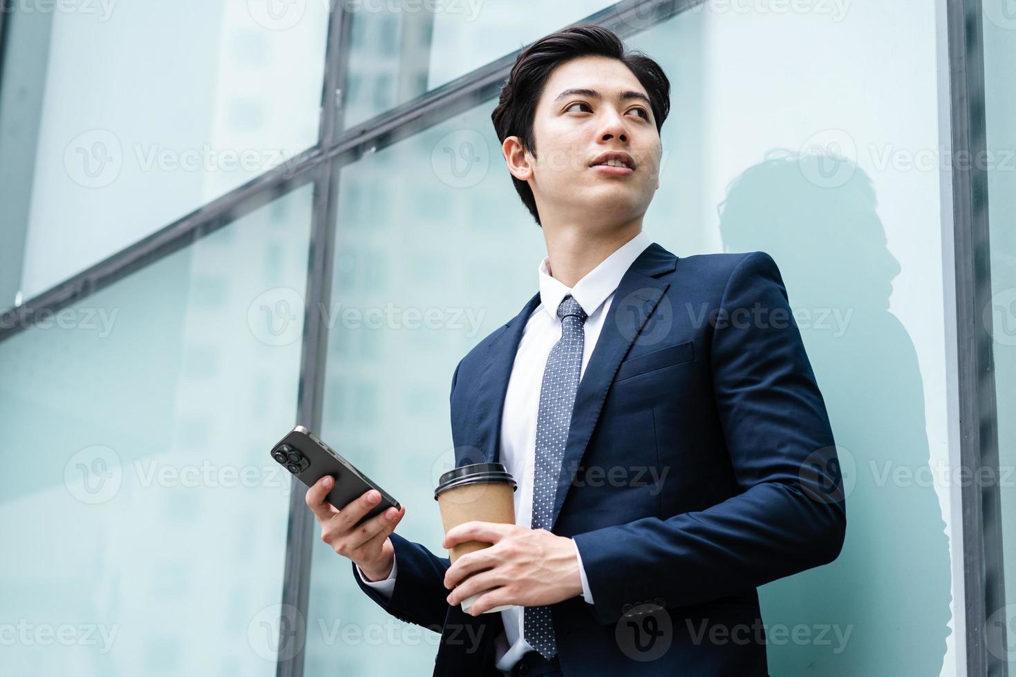 bild av ung asiatisk affärsman med glasbyggnadsbakgrund foto
