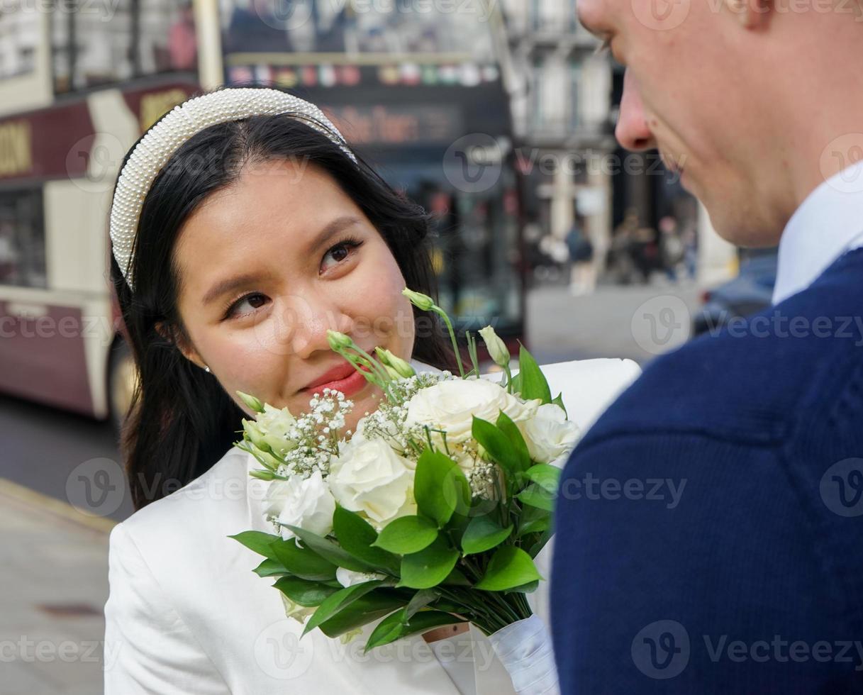 nygifta par av olika nationaliteter ute på en fotografering före bröllopet i london. mannen är brittiska asiatiska kvinnor foto