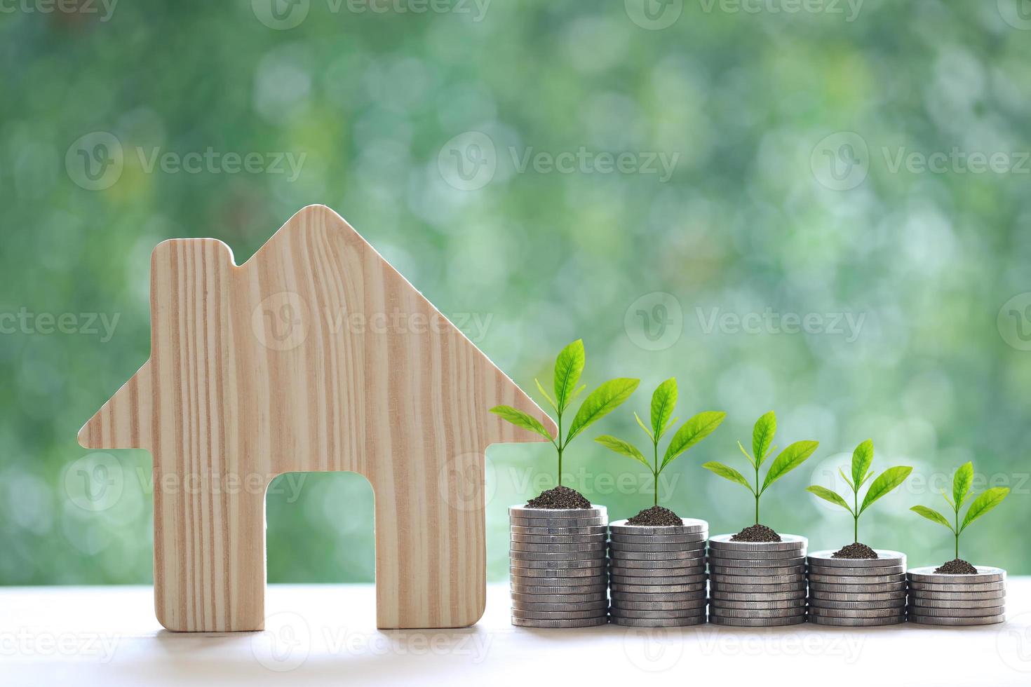 modellhus och träd som växer på en hög med myntpengar på naturlig grön bakgrund, affärsinvestering och fastighetskoncept foto
