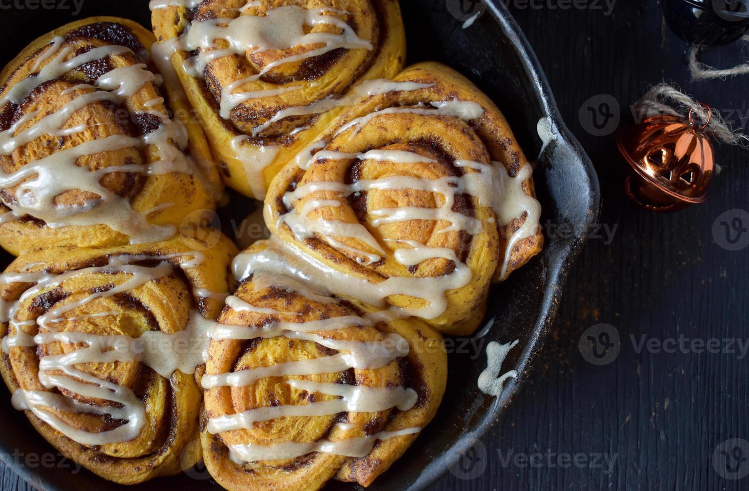 gjutjärnspanna med halloween pumpa kanelbullar överdrålad med vit glasyr platt lägg foto