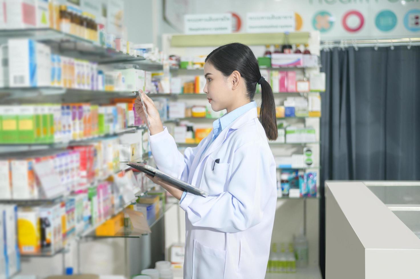 porträtt av kvinnlig apotekare som använder tablett i ett modernt apotek. foto