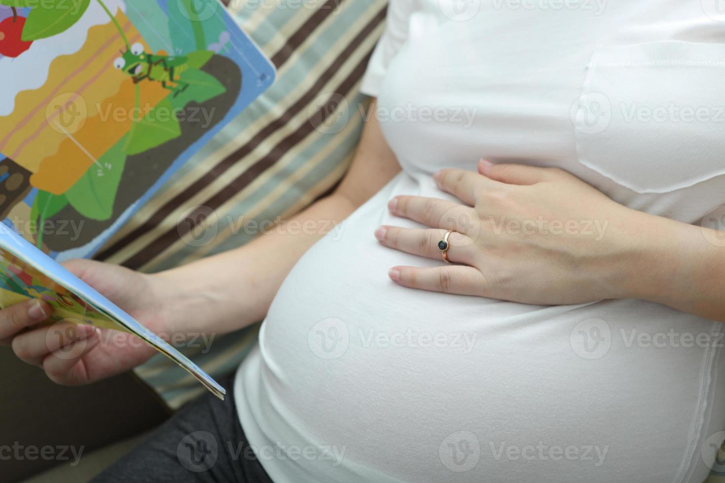 en gravid kvinna läser sagor för sitt ofödda barn, frisk för ett nytt familjekoncept. foto