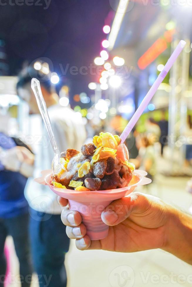 dessertglass och frukostflingor på toppen i mannens hand på foodtruck och foodstreet event., thailand. foto