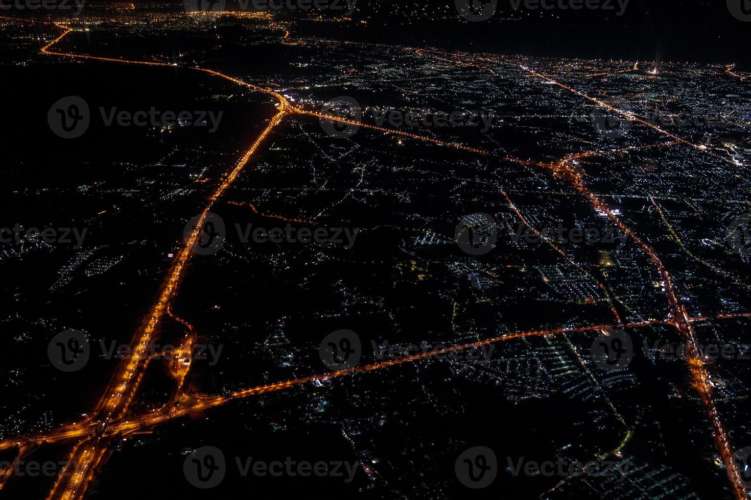 nattvy från jetplanet i skymningstid med den röda himlen och stadens ljus. foto