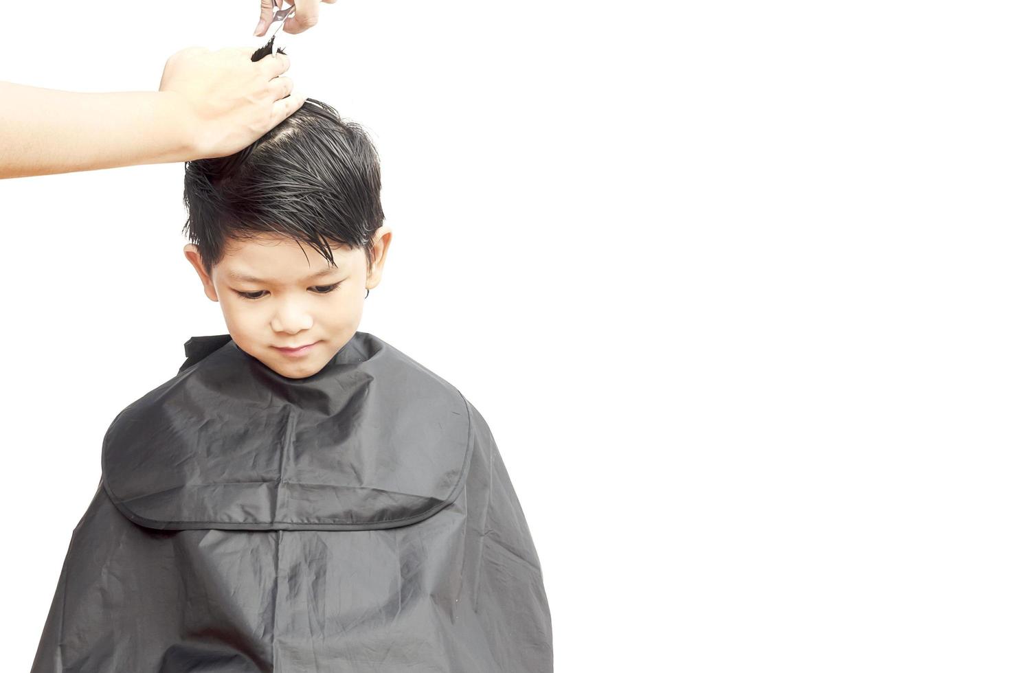 en pojke klipps håret av frisören isolerad över vit bakgrund foto
