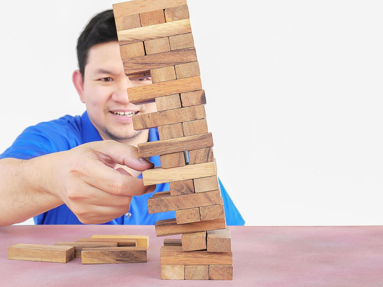 asiatisk kille spelar jenga, ett träklossstornspel för att träna fysisk och mental skicklighet foto