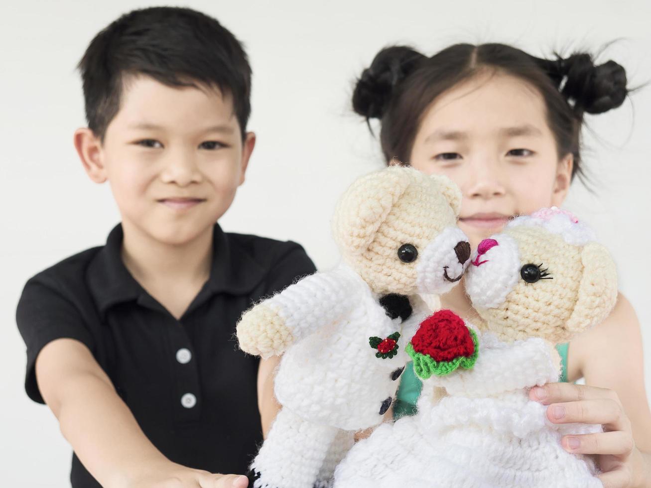 asiatiska barn leker bröllopsbjörndockor foto