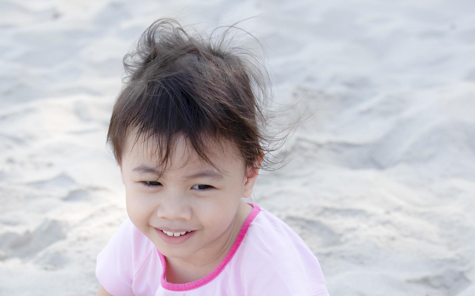 positiv charmig 4 år gammal söt asiatisk tjej, litet förskolebarn som ler och tittar åt höger foto