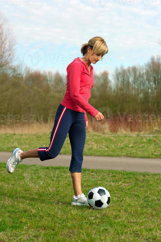 idrottskvinna som sparkar en boll foto