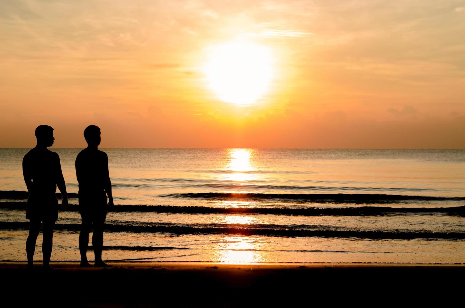 siluettbilden av det homosexuella paret som står tillsammans på stranden. foto