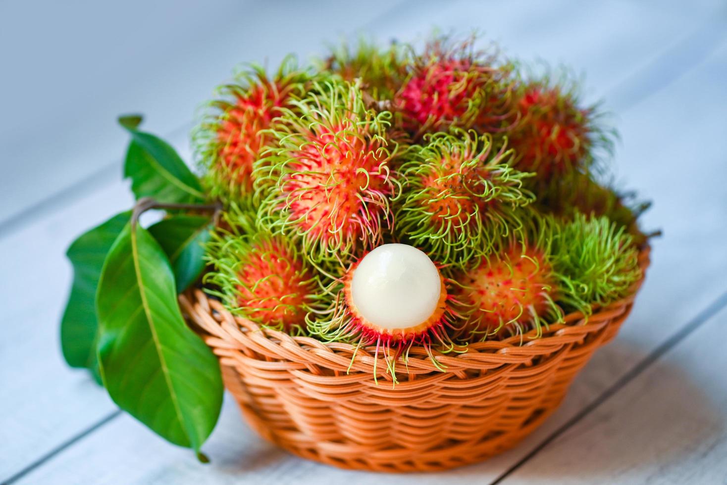 färsk och mogen rambutan söt tropisk frukt skalad rambutan med blad, rambutanfrukt på korgbakgrundsskörd från trädgårdens rambutanträd foto