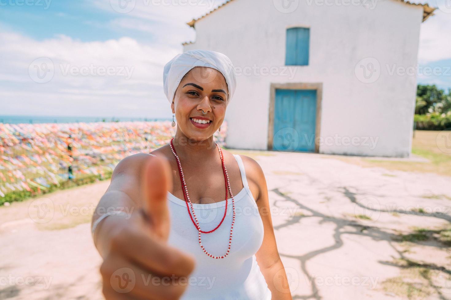 glad brasiliansk kvinna klädd i traditionell bahiansk kostym, med tummen upp i porto seguros historiska centrum foto