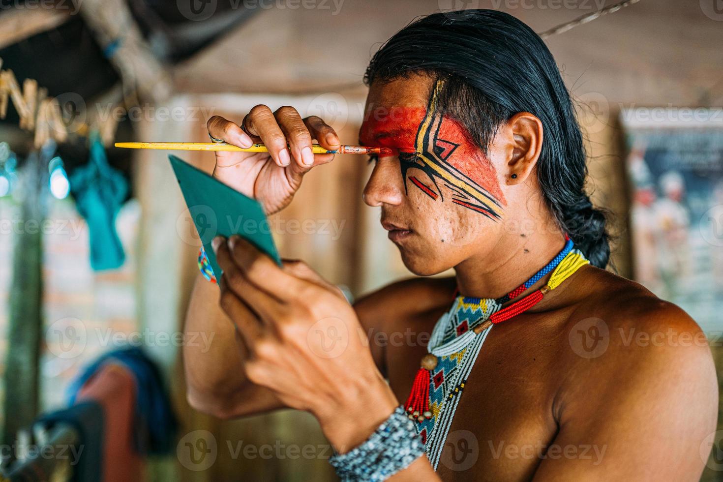 indian från pataxo-stammen, använda en spegel och göra ansiktsmålning. foto