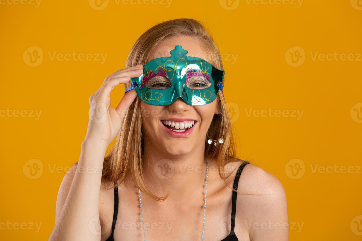 vacker kvinna klädd för karnevalskväll. leende kvinna redo att njuta av karnevalen med en färgglad mask. foto