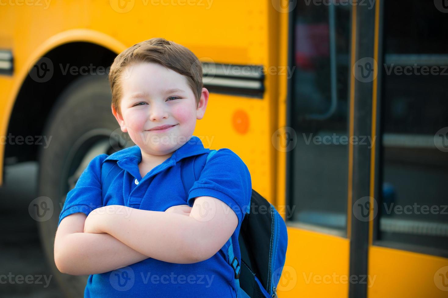 glad ung pojke framför skolbussen foto