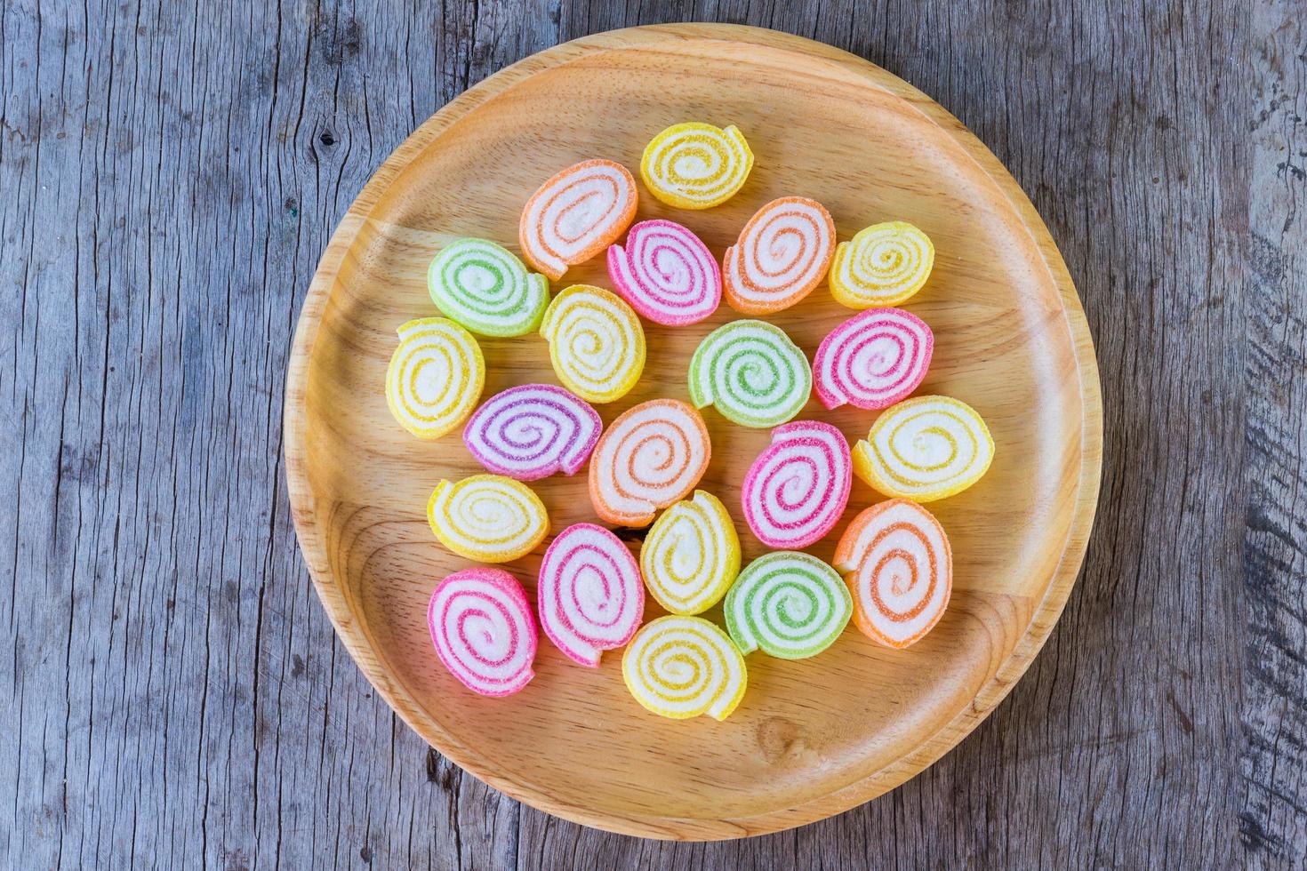 färgglada gummigodis på träfat och på träbakgrund. kopiera utrymme bakgrund och textur foto