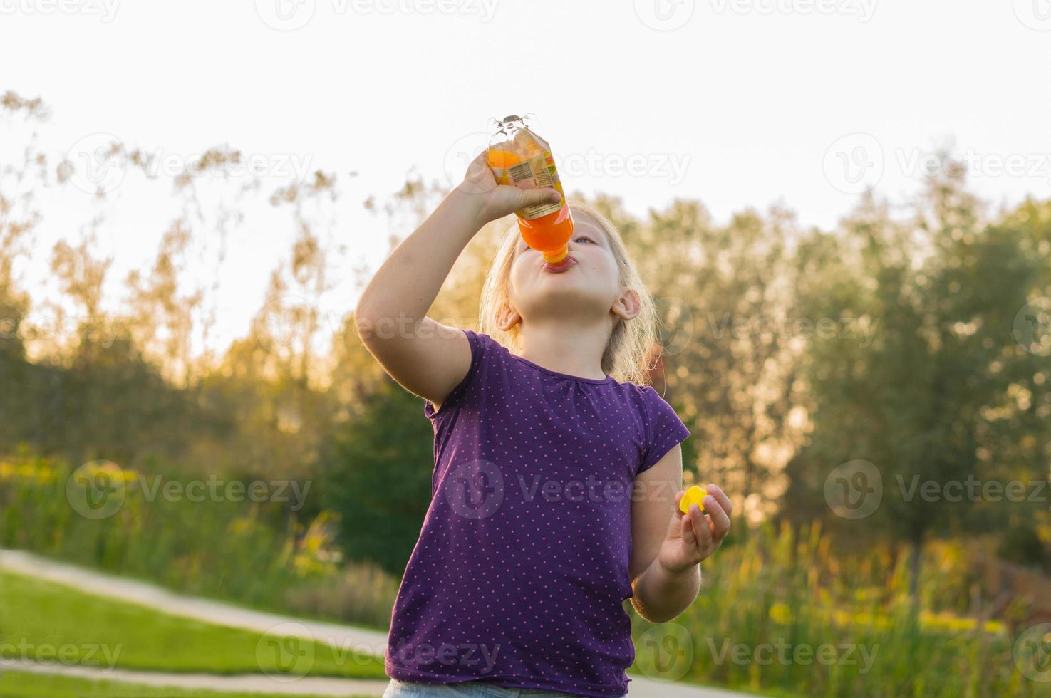flickan dricker juice från flaskan foto