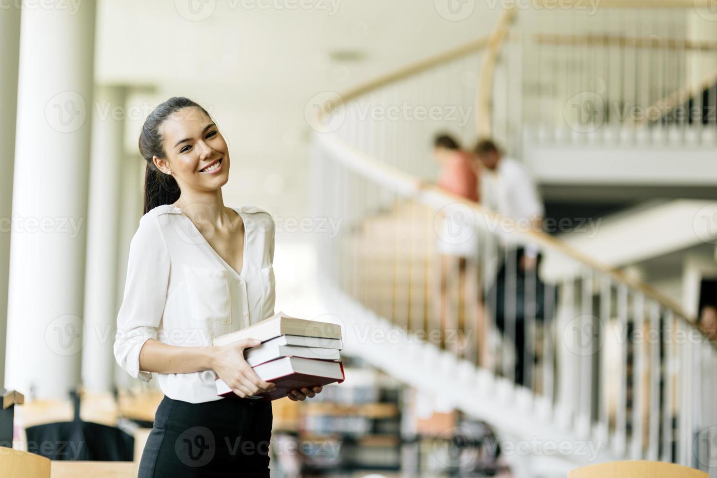 vacker kvinna med böcker i ett bibliotek foto