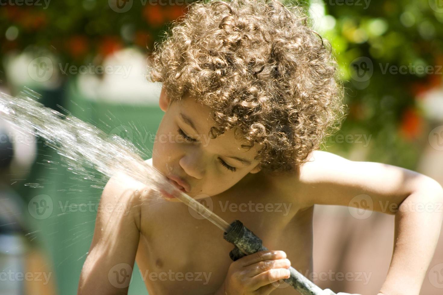 pojke dricker vatten från slangen foto