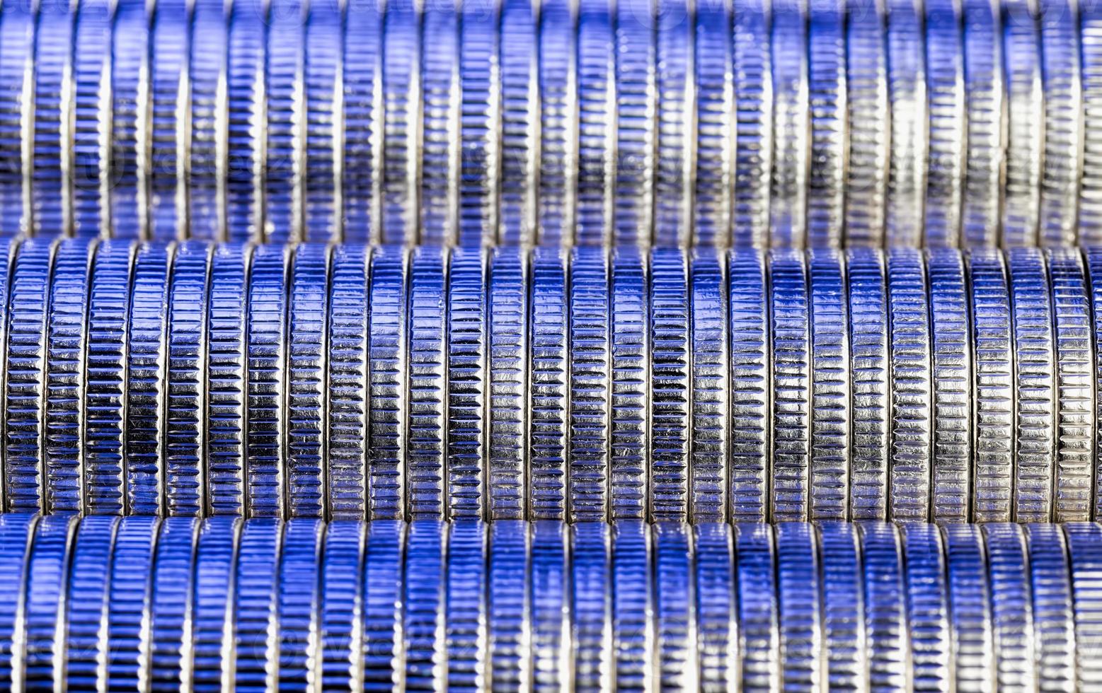 många runda metallmynt av silverfärg upplysta i blått foto