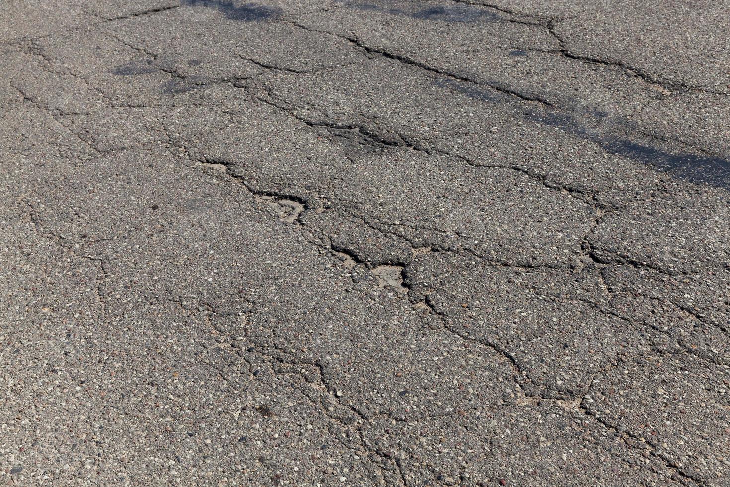 en asfalterad väg med mycket hål och skador foto