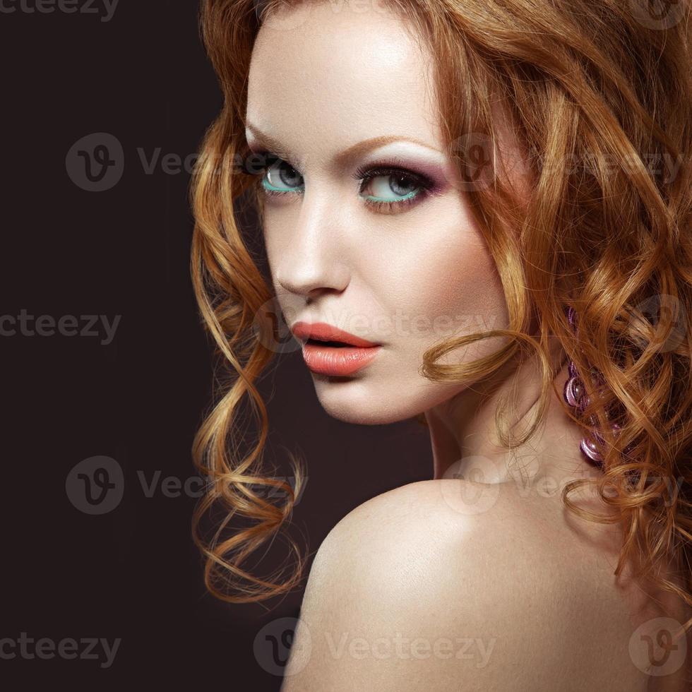 vacker rödhårig tjej med ljus makeup och lockar. foto