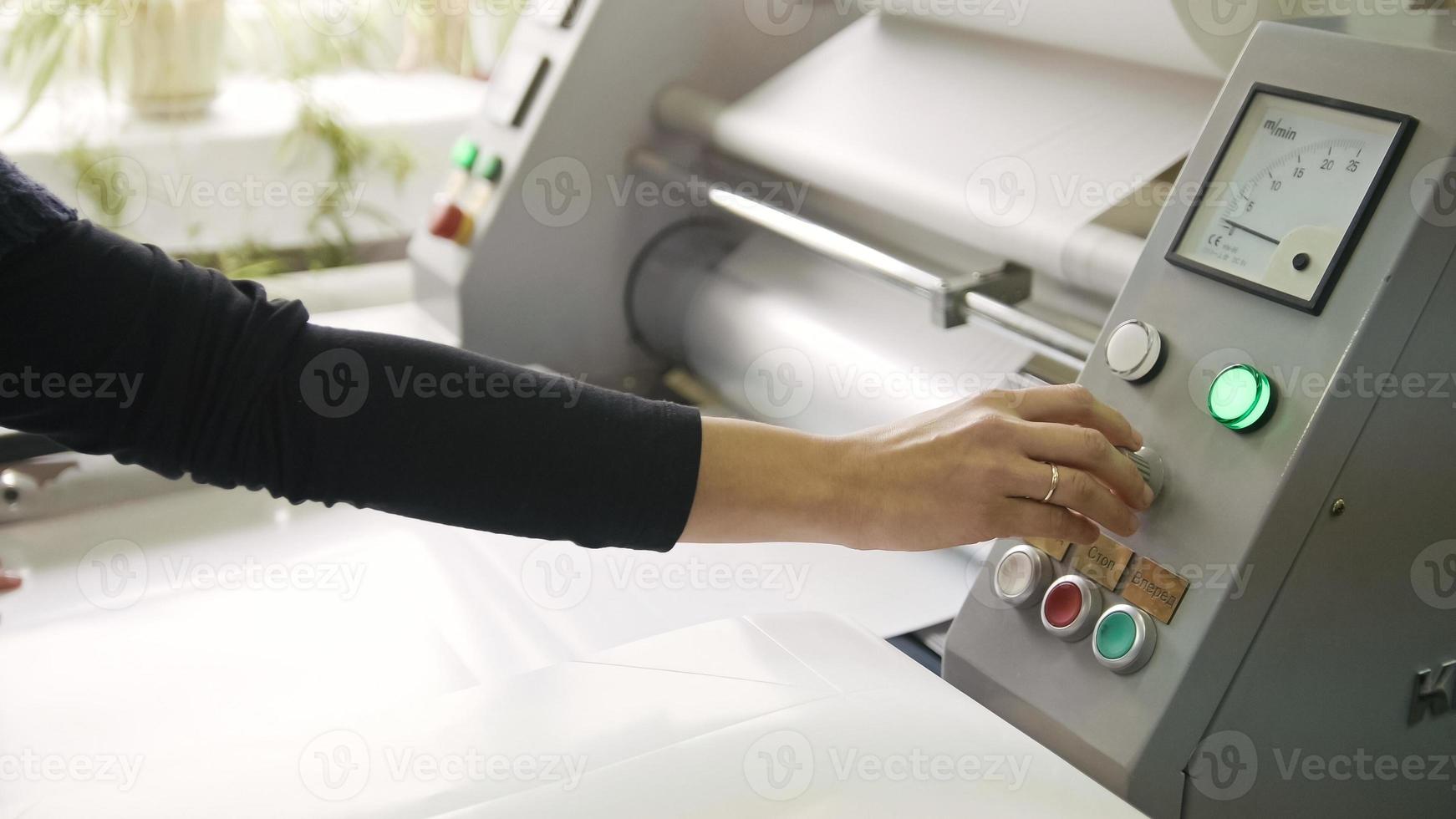 kvinnans arbetare hand på arbetande tryckmaskin, polygraf industri foto