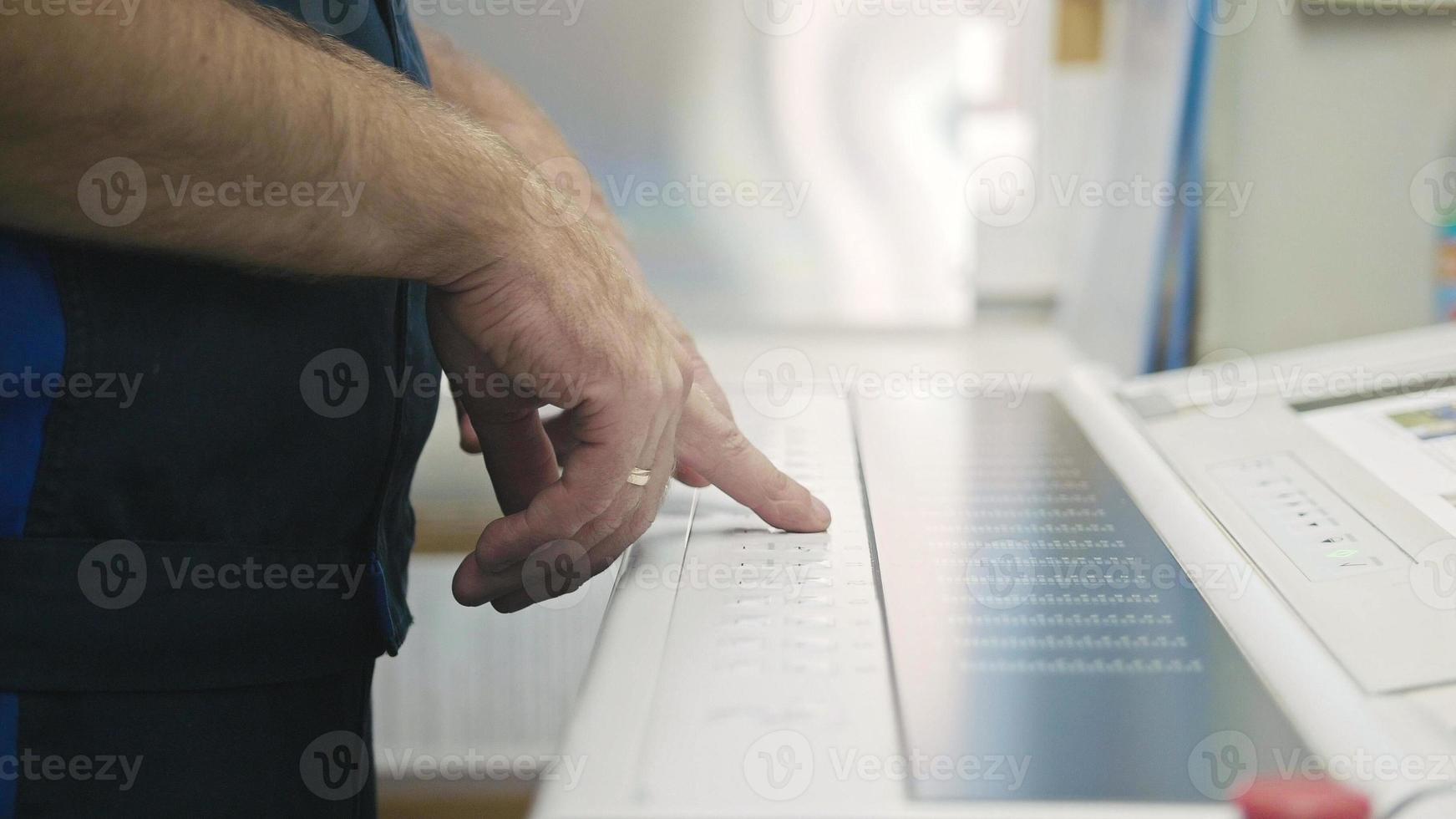 industriarbetare. man som använder kontrollpanelen på skrivaren. foto