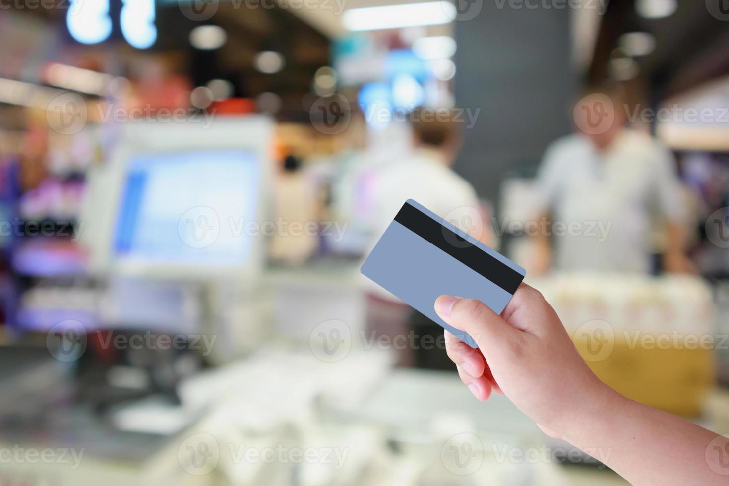 handhåll kreditkort med stormarknad kassa kassadisk med kund oskärpa bakgrund foto