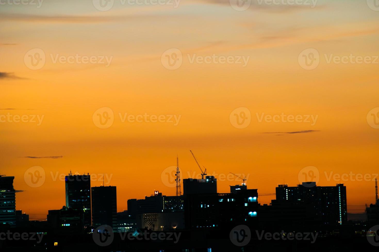 ger en varm känsla, solnedgång bakom stadsbyggnaden, siluett stadens höga byggnader, byggnadssilhuett igen vacker himmelbakgrund och frihetskoncept. foto