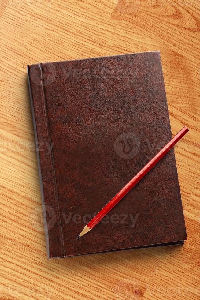 mörk tom anteckningsbok med röd penna foto