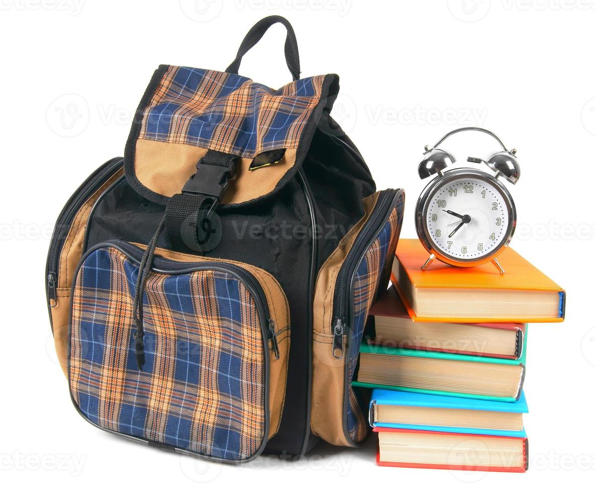 skolryggsäck, böcker och väckarklocka. foto