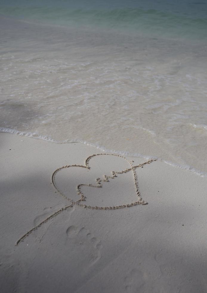 hjärtan ritade på sanden på en strand foto