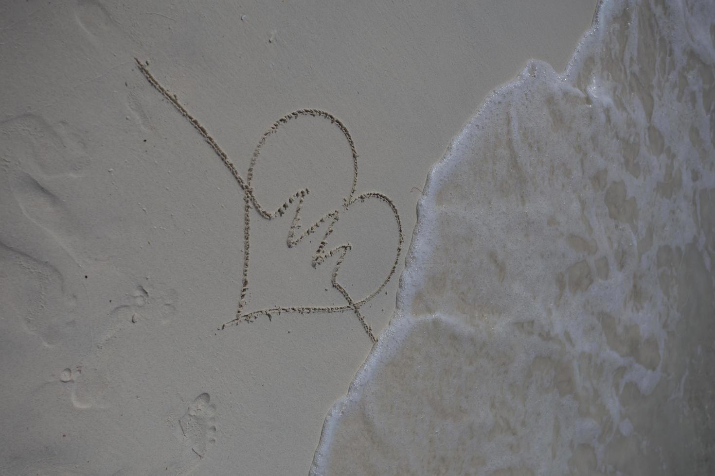 hjärtan ritade på sanden på en strand foto